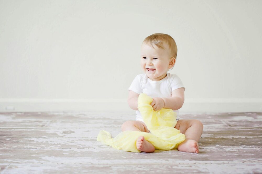 IVF treatment on the NHS, illustrated by a baby sitting on a wooden floor.