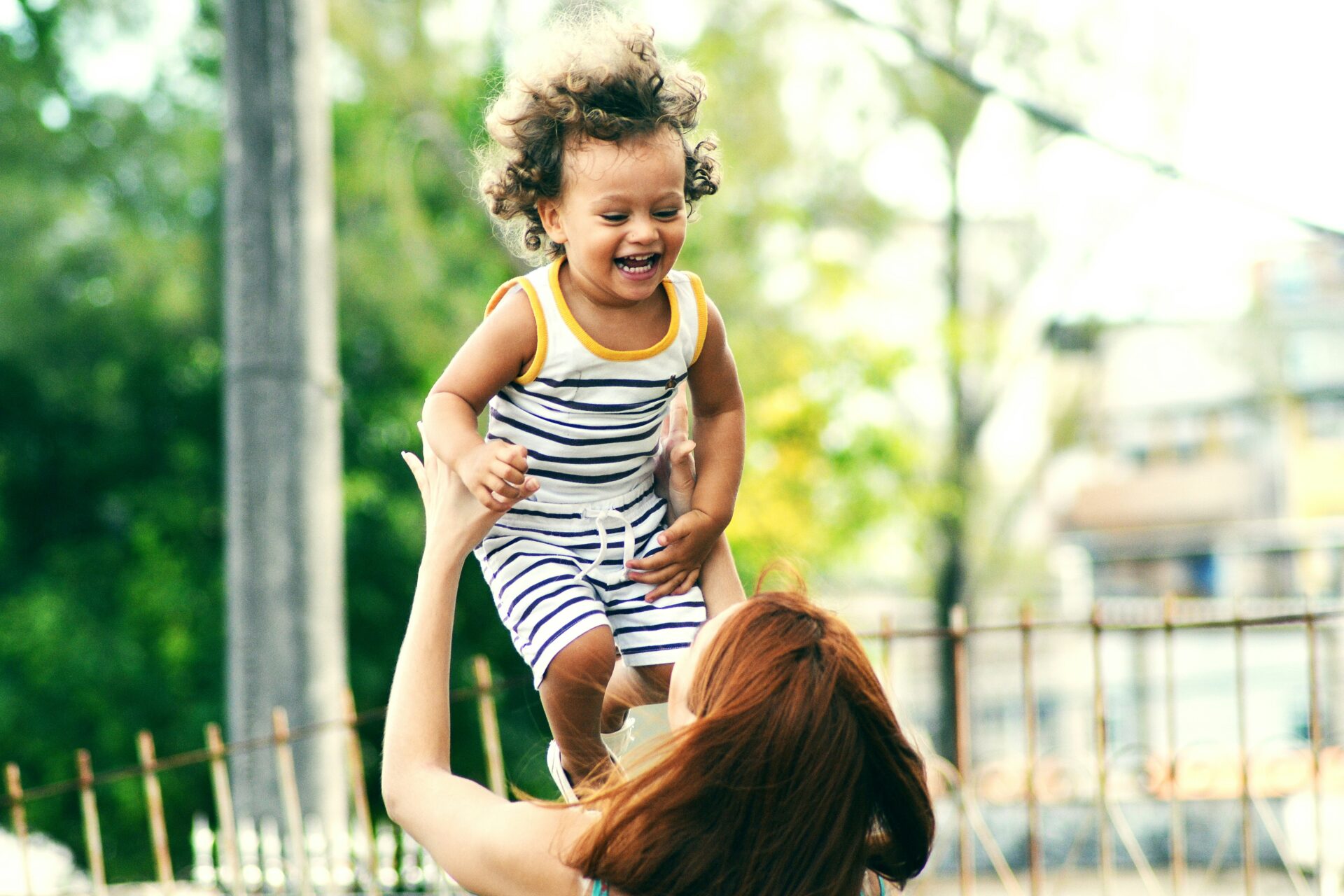 Why Choose Kind iVF? A photo of a young child being held up in the air.